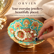 Turquoise floral bowl holding visible pearl jewellery and a blue-stone ring on a dressing table.